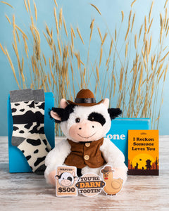 Photo of cow plushie with vest and hat, blue Somone Loves You box, notecard, cow stickers, cow socks, and a promotional card