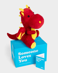 Side view photo of yellow and red Duke the Dragon plushie, blue Someone Loves you Box, and note card