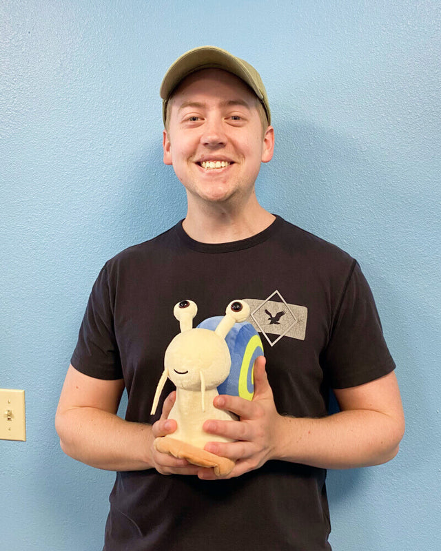 Photo of person smiling while holding Shelly the Snail plushie