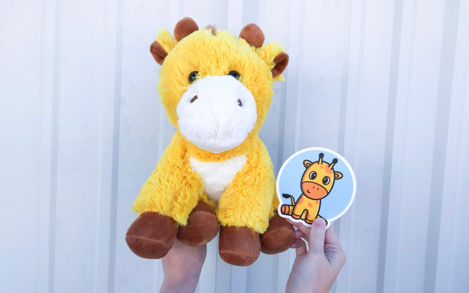 person holding giraffe stuffed animal with matching sticker in the air
