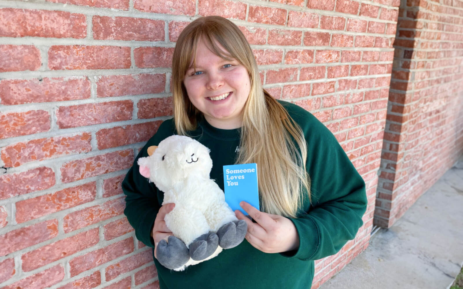 woman holding gus the goat stuffed animal and notecard