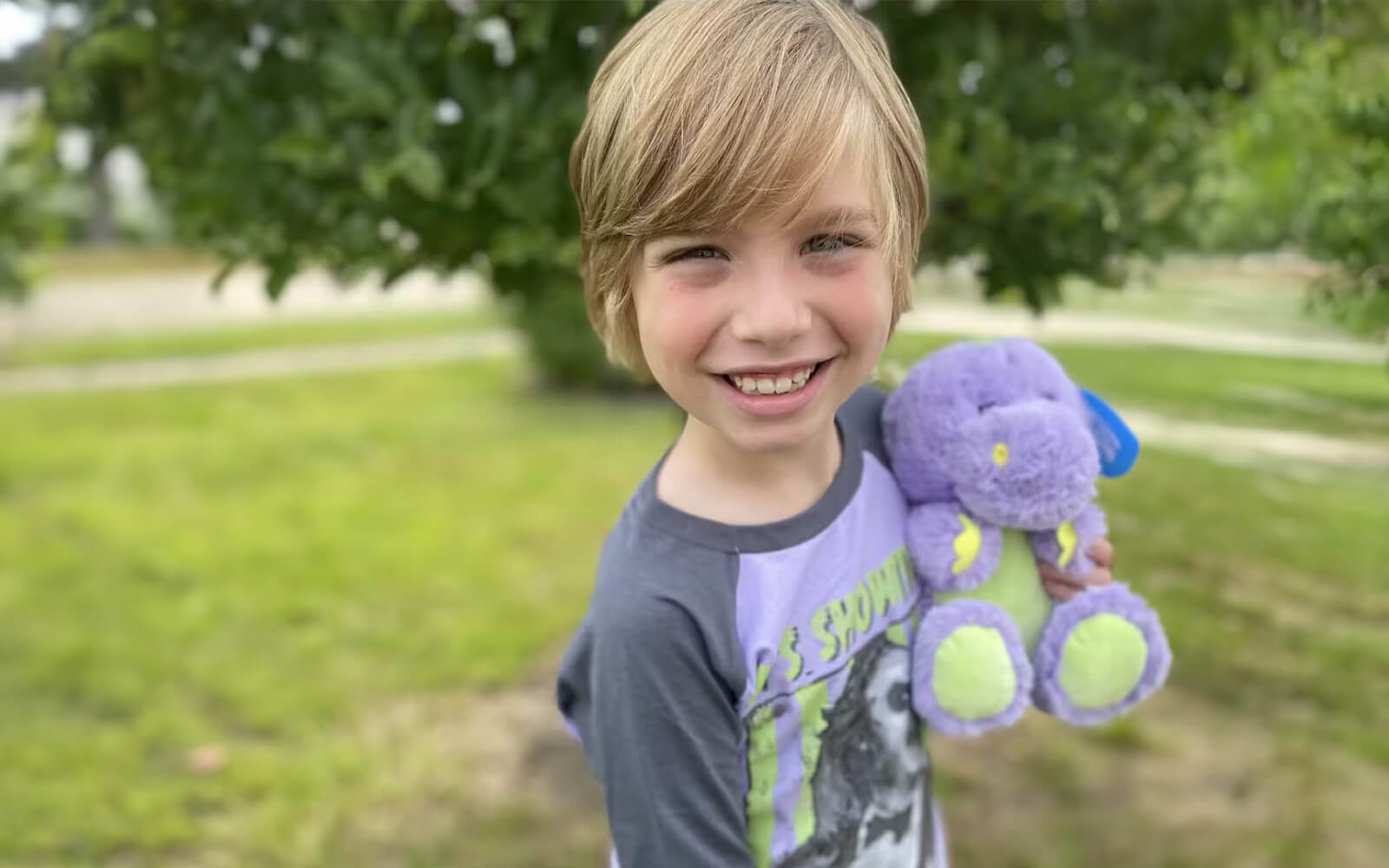 An image of a child smiling holding Dexter the Dinosaur