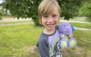 An image of a child smiling holding Dexter the Dinosaur