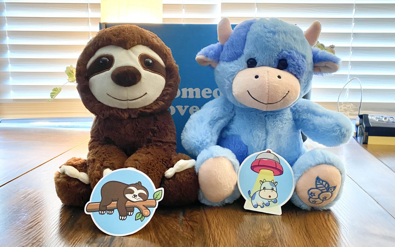 sloth and blue cow stuffed animal sitting on table with matching stickers