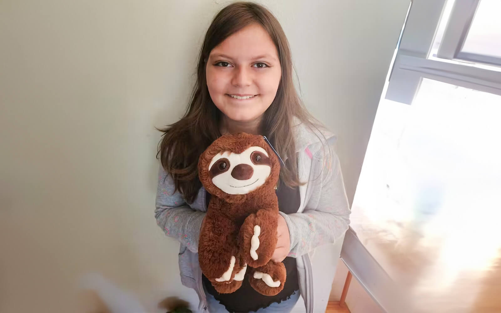 An image of a girl smiling holding Sam the Sloth