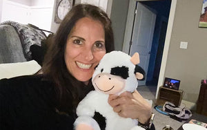 An image of a woman smiling while hugging Cooper the Cow against her cheek