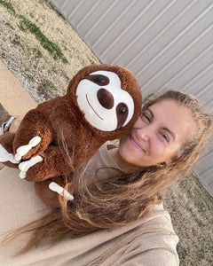Photo of person smiling holding 14 inch Jumbo Sam the Sloth plushie next to face