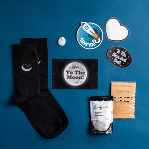 Photo of items included in To The Moon & Back Bundle: Socks, promo card, Howlite worry stone, 3 stickers, bracelets, and Spa Bath Soak
