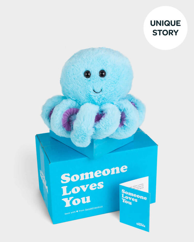 Photo of blue Ollie the Octopus with purple tentacles plushie, Someone Loves You box, and notecard