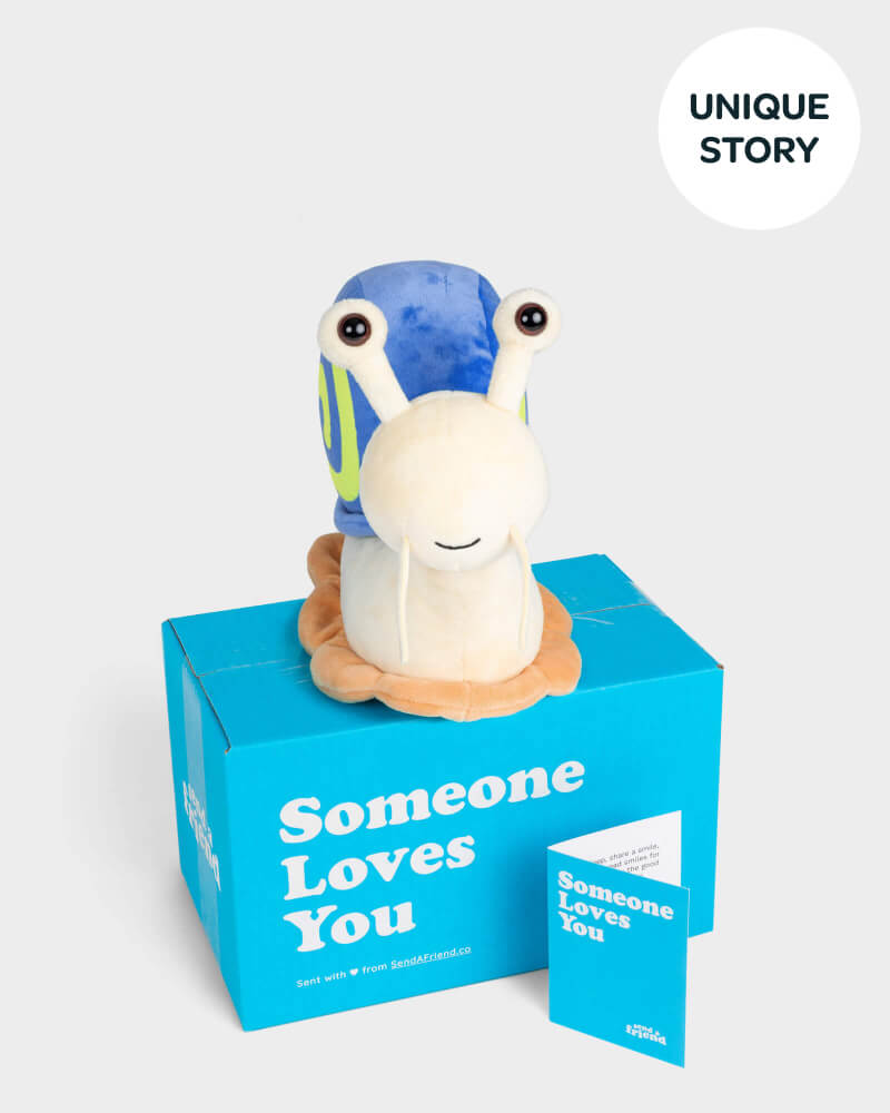 Blue shelled, white snail plushie sitting on top of SendAFriend box and next to notecard both in signature blue color