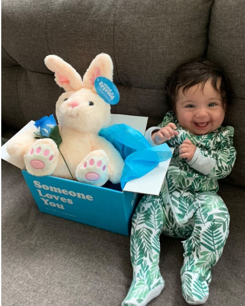 Photo of baby sitting on couch next to Someone Loves You box with Benny the Bunny in box and blue rose available for additional $3. 