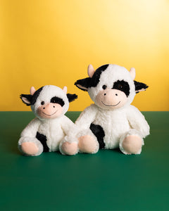 Photo of 10 inch and 14 inch black and white Cooper the Cow plushies sitting side by side 
