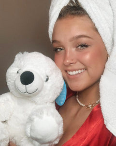 Photo of person holding white Peaches the Polar bear plushie near face and smiling