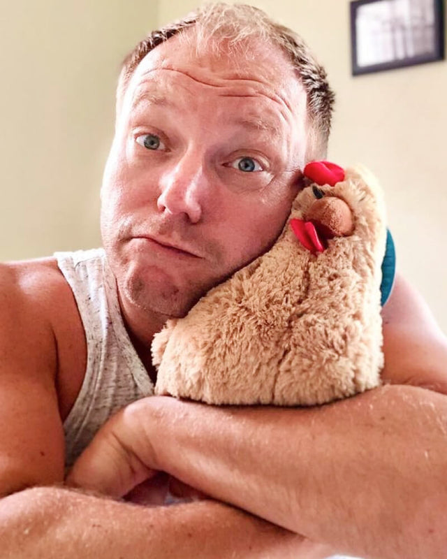 Photo of person hugging tan Rowdy the Rooster plushie to their face