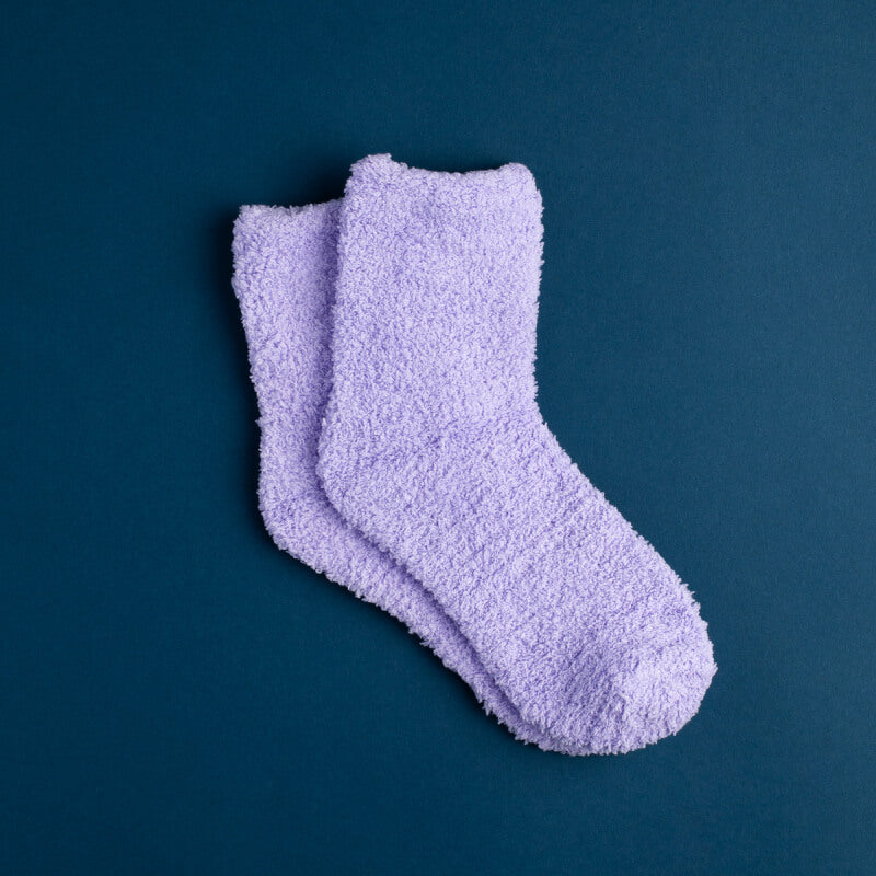 Photo of a pair of purple fuzzy socks on a blue background