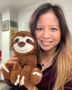 Photo of person smiling while holding brown Sam the Sloth plushie near face